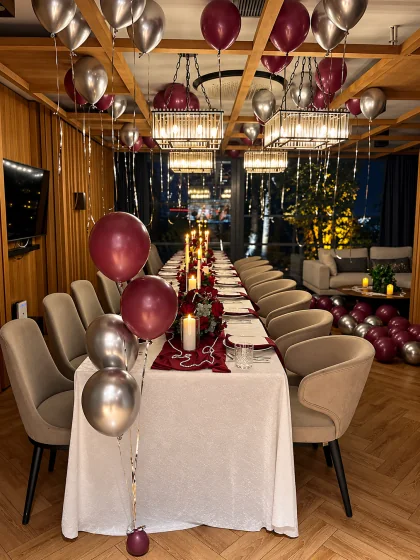 Bordo çiçekler, mumlar ve tavan balonlarıyla yetişkin doğum günü sofrası