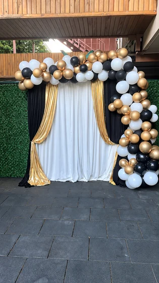 Altın ve beyaz perdelerle siyah beyaz altın balonlardan oluşan etkinlik fotoğraf fonu