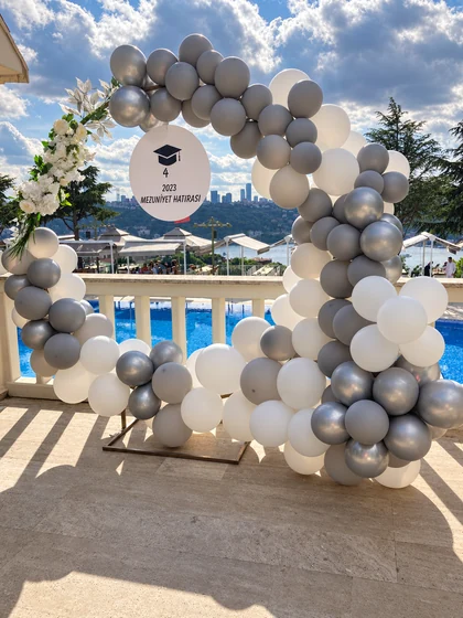 Havuz terasında beyaz çiçekler, beyaz gümüş balon çemberi ve 4 2023 Mezuniyet Hatırası tabelası