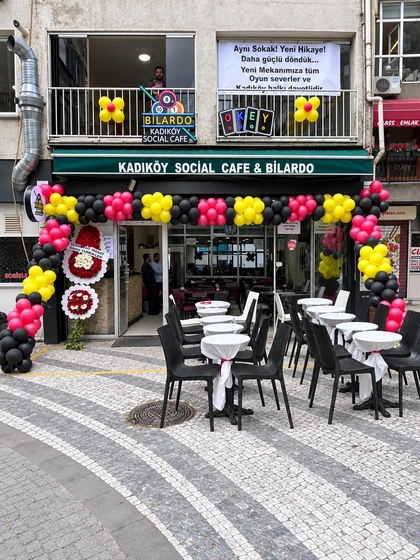 Kadıköy Social Cafe önünde siyah, pembe ve sarı balon süslemeleri ile beyaz örtülü bistro masalar